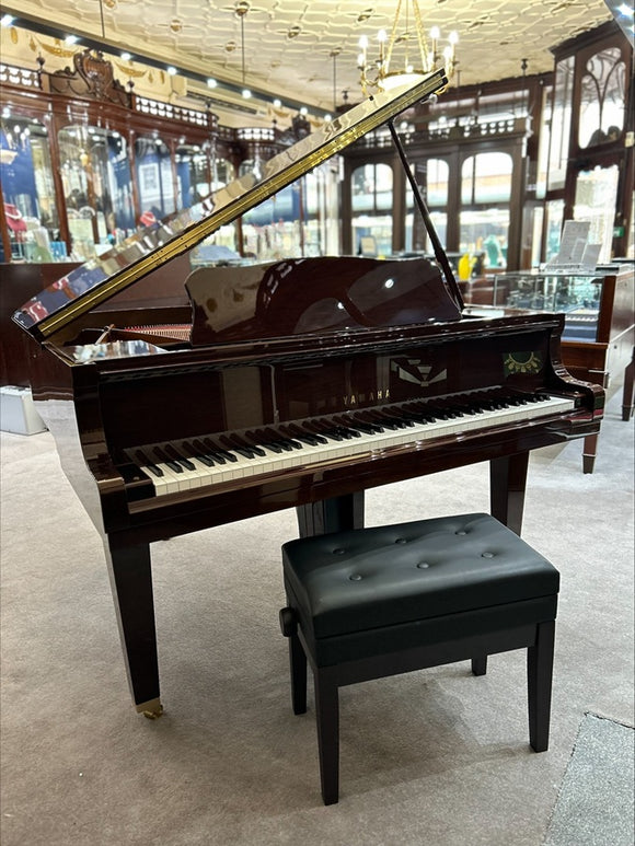 A Yamaha GB1 Disklavier Enspire ST Grand Piano with the lid open, showing the interior of the piano and the keyboard. The piano is placed in a showroom setting with a bench in front.